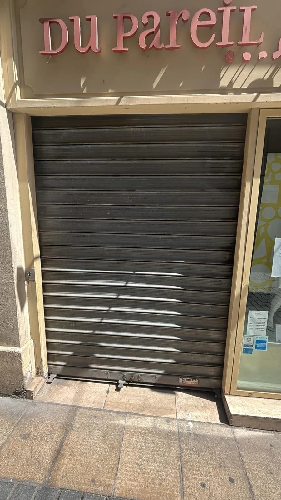 Rideau métallique à lames pleines devant une boutique de centre-ville
