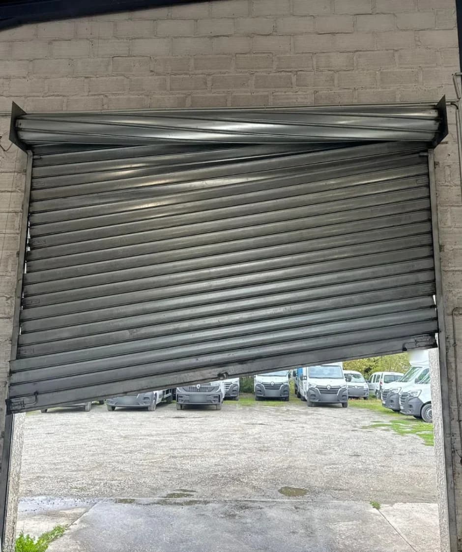 Tablier de rideau métallique bloqué en biais dans l’ouverture d’un dépôt