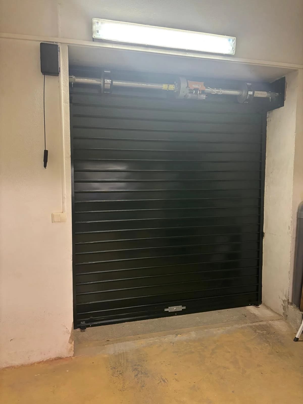 Axe motorisé et moteur central d'un rideau métallique de garage, vus de l'intérieur