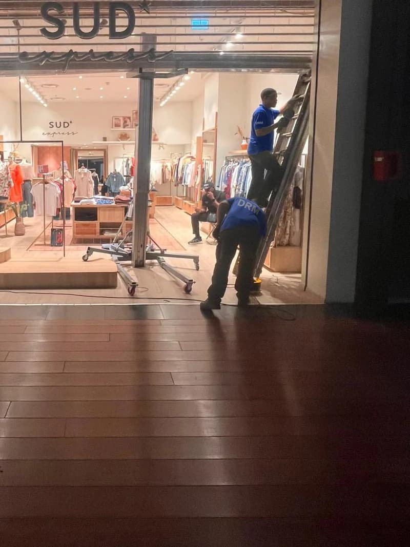 Techniciens DRM posant un rideau polycarbonate motorisé dans une boutique de mode en centre commercial