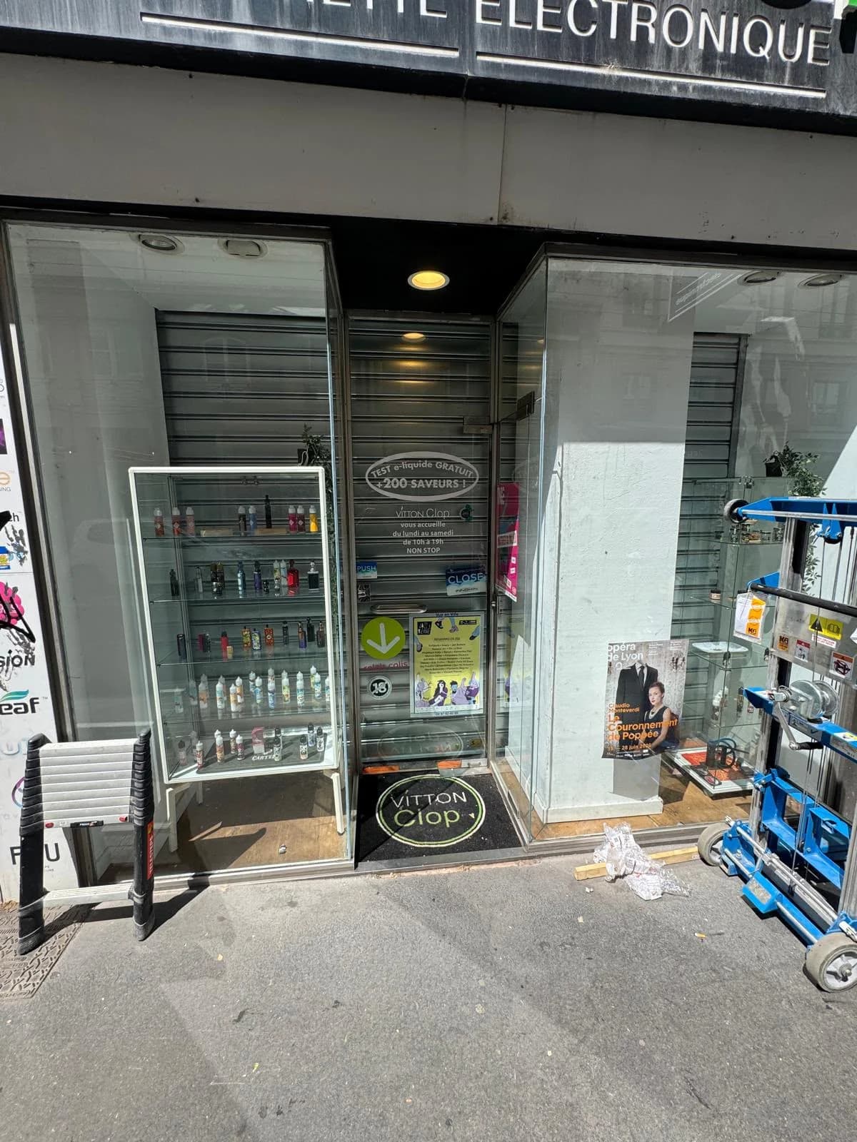 Lève-rideau sur le trottoir devant une boutique, pendant la pose de son rideau métallique intérieur