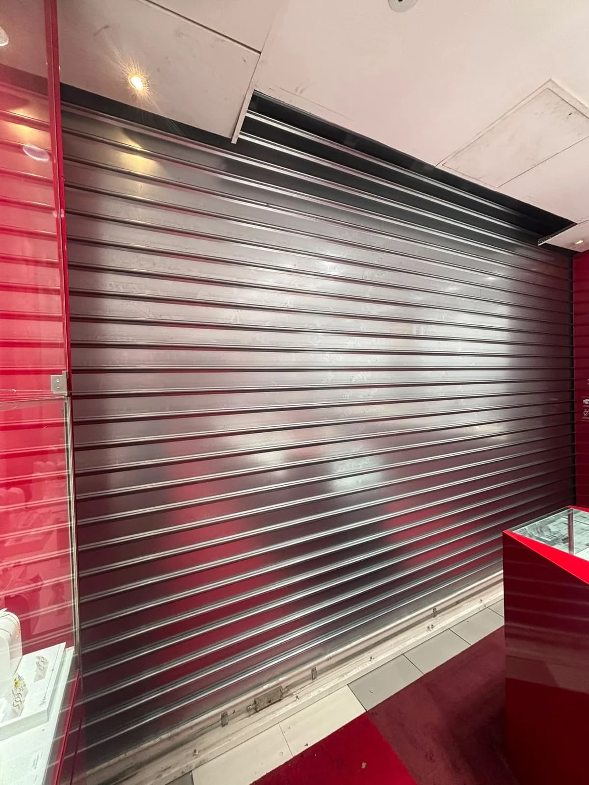 Rideau métallique à lames pleines posé côté intérieur, derrière la vitrine