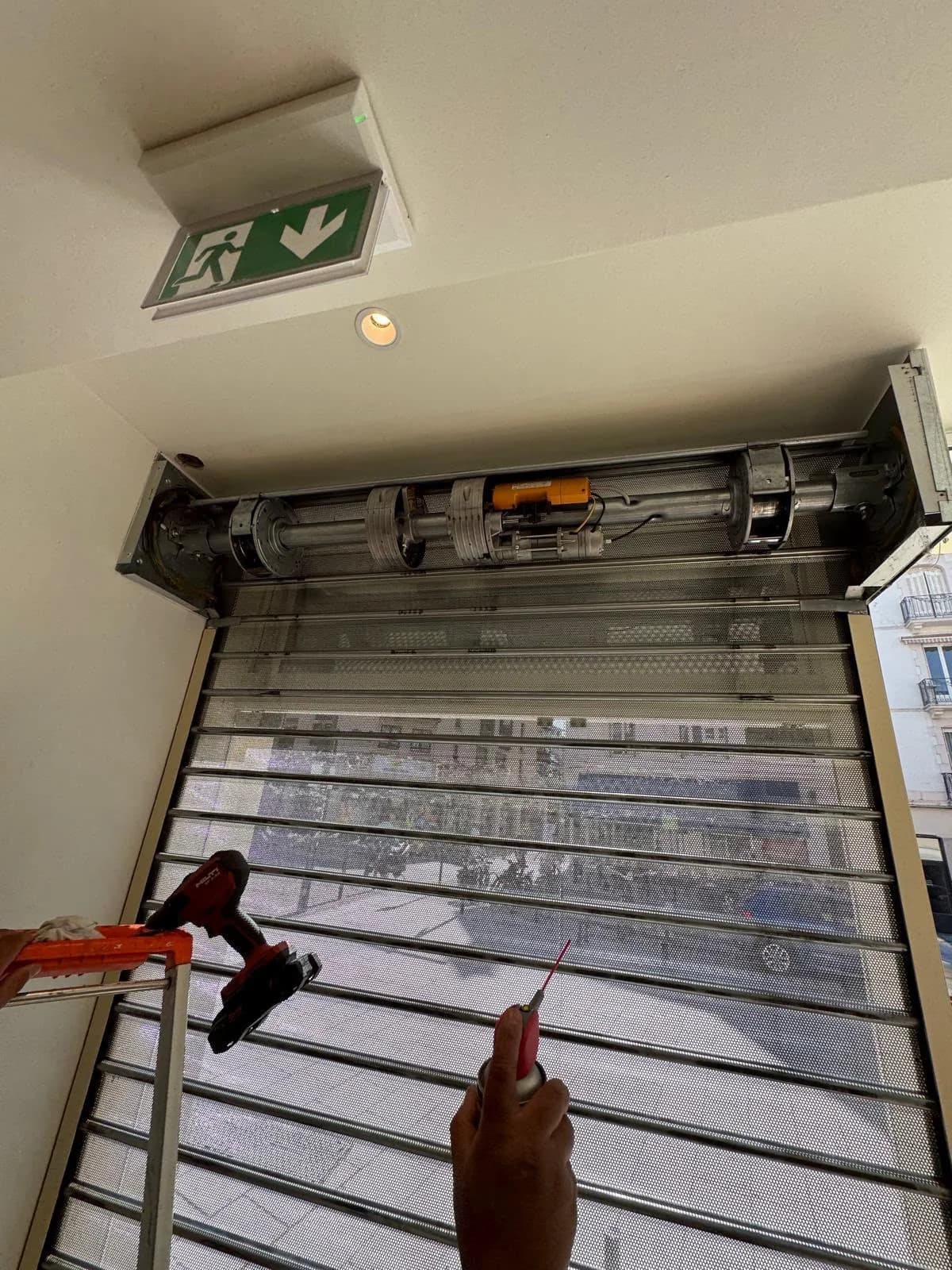 Axe et moteur d’un rideau micro-perforé, capot ouvert, pendant son entretien